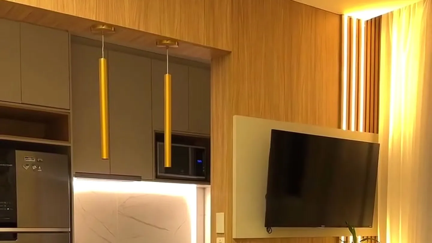 Cozinha planejada em madeira integrada à sala com TV